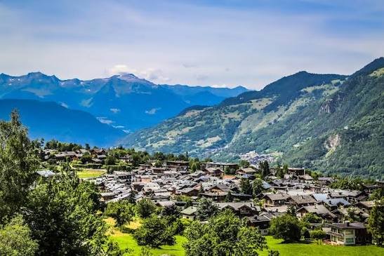 Alpine village of chalets below snow-capped peaks