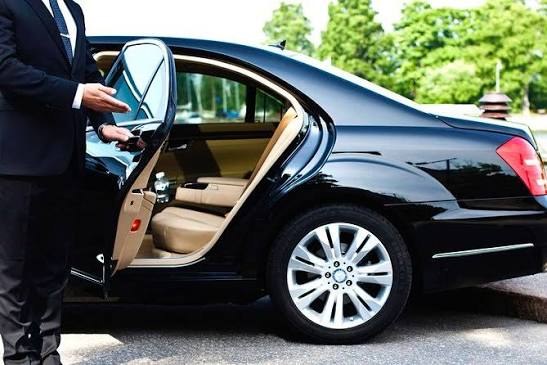 Chauffeur opening the door of a black luxury sedan